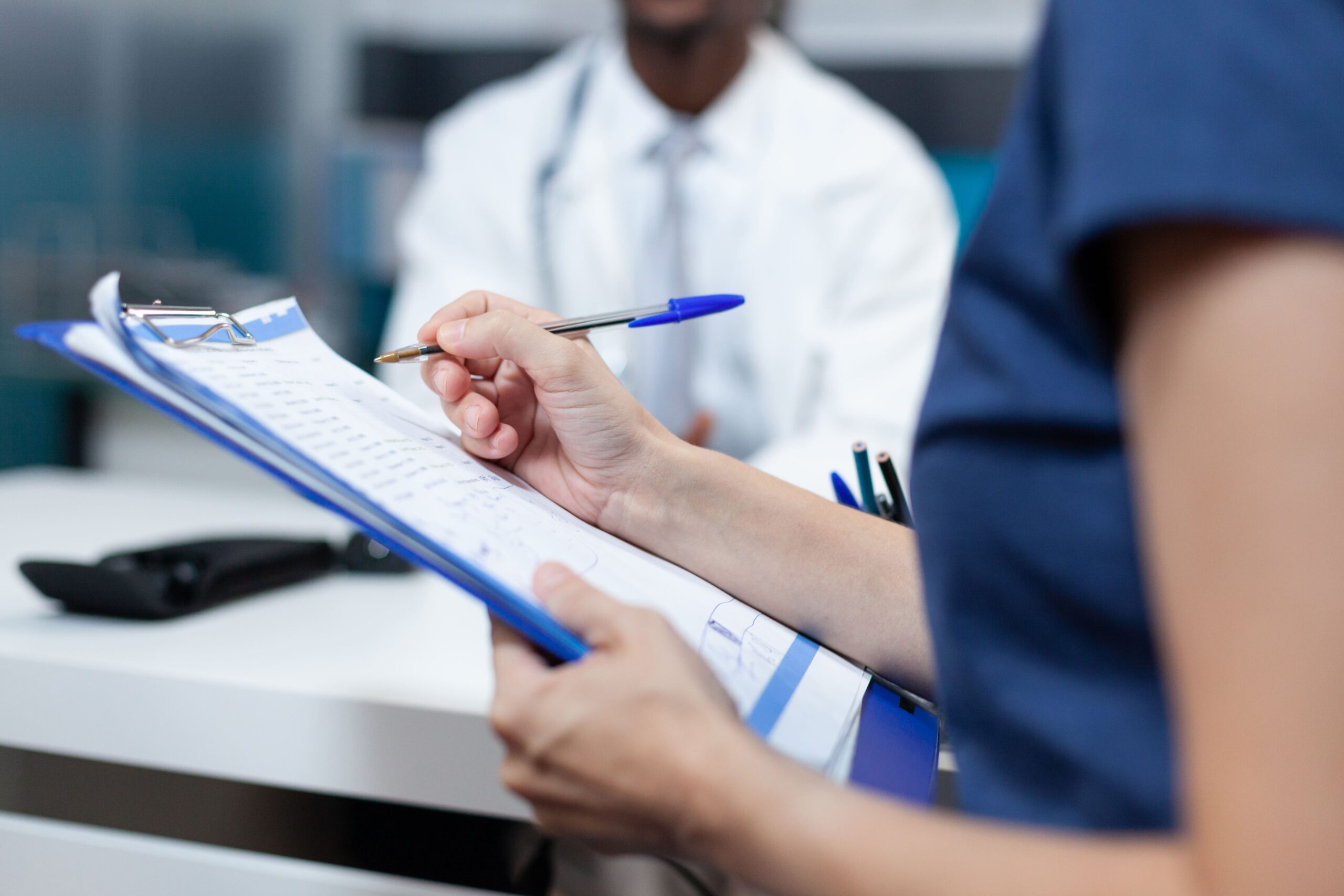 mão segurando uma prancheta e realizando uma auditoria médica