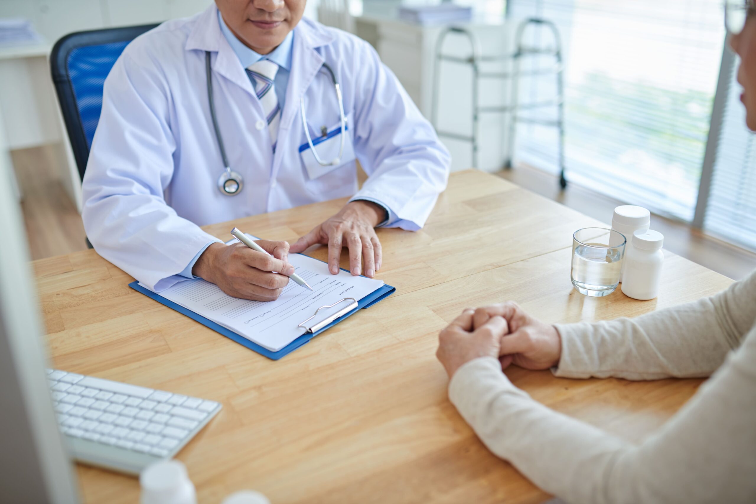 médico escrevendo na prancheta e atendendo paciente