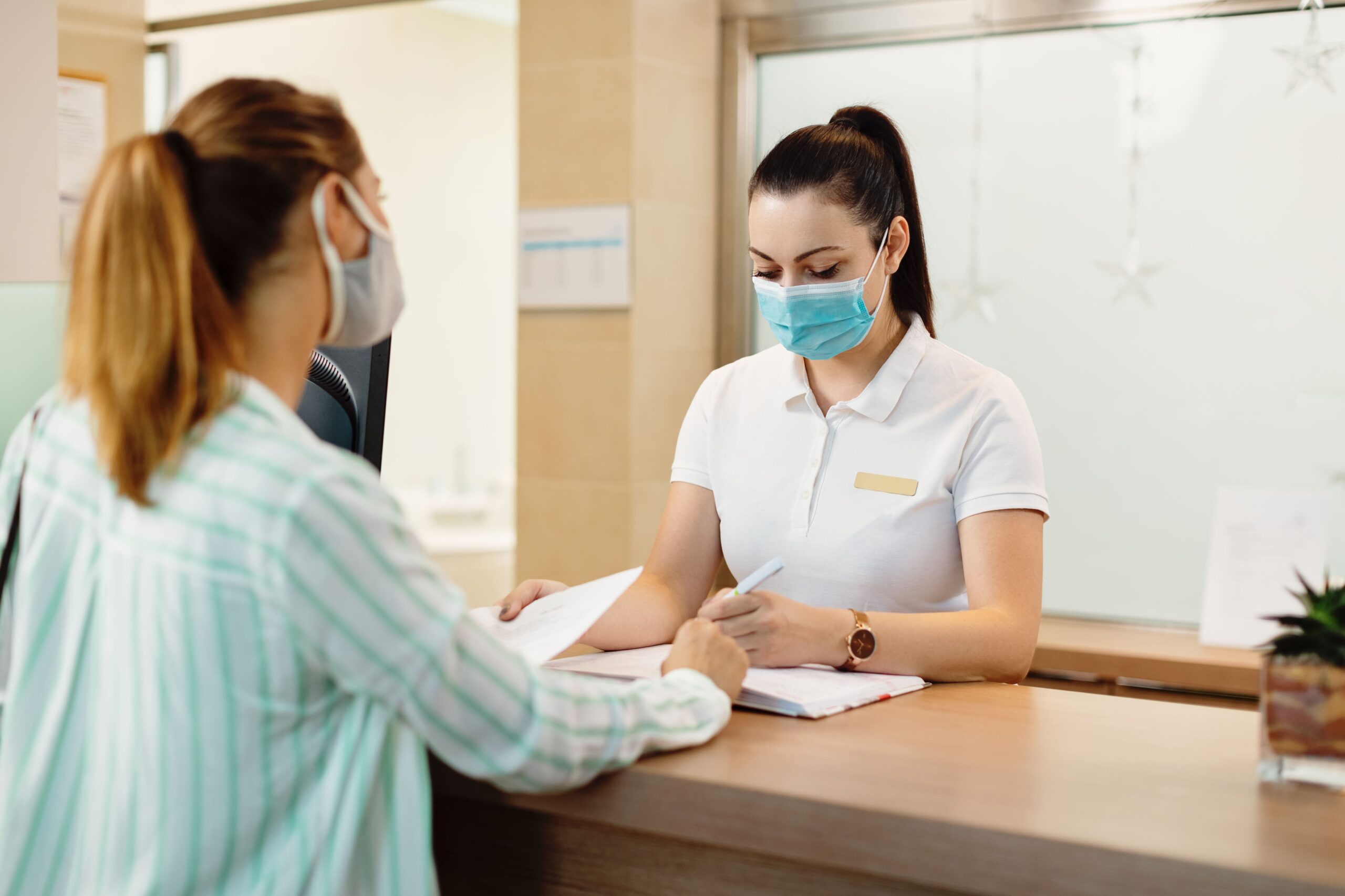 Mulheres com máscara conversando na recepção de clínica